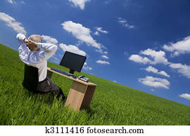 Man Relaxing At Office Desk In a Green Field