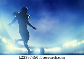 American football player kicking the ball, kickoff. Stadium lights American football player kicking the ball, kickoff. Stadium lights
