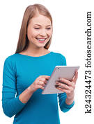 Thing that is always with me. Beautiful young women holding digital tablet and smiling while standing against white background.