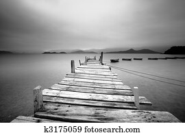 Looking over a pier and boats, black and white