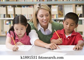 Kindergarten teacher helping students with writing skills Kindergarten teacher helping students with writing skills