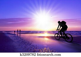 mountain biker on beach and sunset mountain biker on beach and sunset