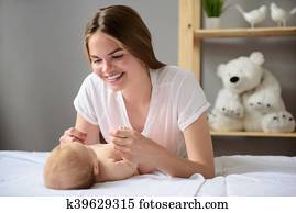 Happy mother playing with her baby girl at home