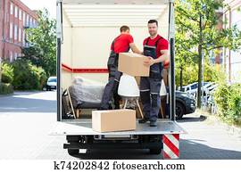 Young Men Stacking The Cardboard Boxes In Moving Truck Young Men Stacking The Cardboard Boxes In Moving Truck