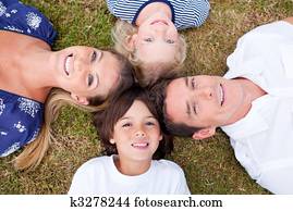 Cheerful family lying in circle on the grass