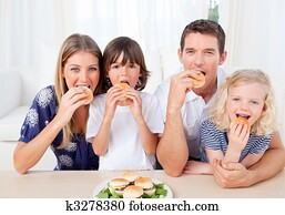 Hungry family eating burgers in the living room