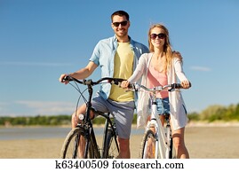 happy young couple riding bicycles at seaside happy young couple riding bicycles at seaside