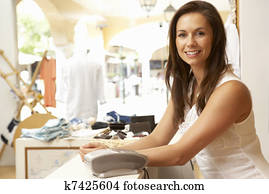 Female Sales Assistant At Checkout Of Clothing Store Female Sales Assistant At Checkout Of Clothing Store