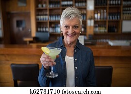 Senior woman having glass of cocktail in bar