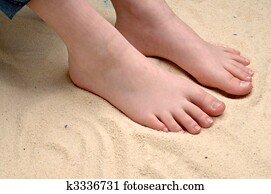 horizontal image of a childs feet in the sand