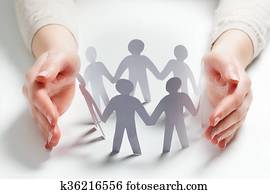 Paper people surrounded by hands in gesture of protection. Concept of insurance Paper people surrounded by hands in gesture of protection. Concept of insurance