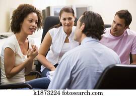 Man giving lecture to three people in computer room Man giving lecture to three people in computer room
