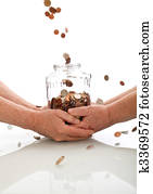 Elderly hands holding jar catching falling coins