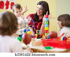 three little girls and female teacher in kindergarten three little girls and female teacher in kindergarten
