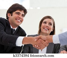 Smiling businessman and his colleague closing a deal with a partner in a meeting