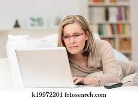 Woman concentrating as she works on a laptop Woman concentrating as she works on a laptop