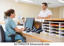 Nurse And Patient Conversing At Reception Desk Nurse And Patient Conversing At Reception Desk