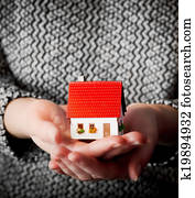 Woman holding a small new house in her hands. Real estate, mortgage
