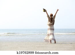 Woman with raised arms at the beach 