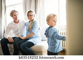 Young parents looking at their toddler son inside in a bedroom.