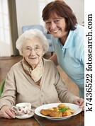 Senior Woman Being Served Meal By Carer
