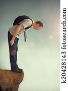 man looking down from a rocky ledge