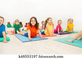 Kids stretching backs on yoga mats in sports club Kids stretching backs on yoga mats in sports club