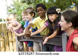 Preschool children playing on playground with teacher Preschool children playing on playground with teacher