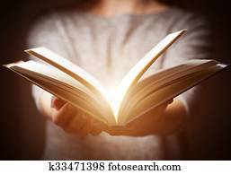 Light coming from book in woman's hands in gesture of giving Light coming from book in woman's hands in gesture of giving
