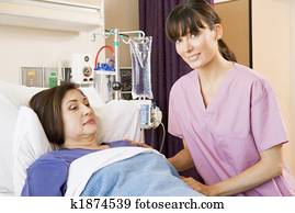 Nurse Helping Senior Woman Lying In Hospital Bed