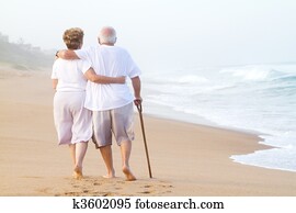 elderly couple strolling on beach