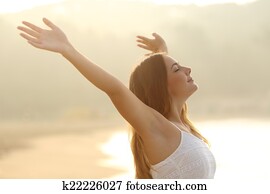 Relaxed woman breathing fresh air raising arms at sunrise