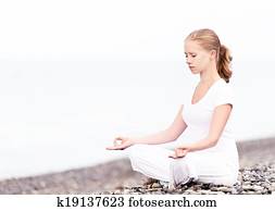 woman meditating in  lotus yoga on beach