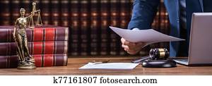 Lawyer Holding Documents Near Mallet And Laptop Lawyer Holding Documents Near Mallet And Laptop