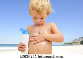 cute child applying  sunscreen  at the beach