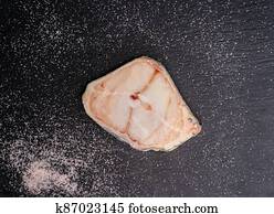 Raw Catfish steak with salt on shale board.