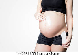 Young healthy pregnant woman with blank tube of cream on her belly. Copy space for text. Young healthy pregnant woman with blank tube of cream on her belly. Copy space for text.