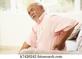 Senior Man Suffering From Back Pain At Home Senior Man Suffering From Back Pain At Home