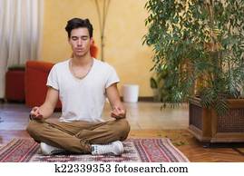 Young man meditating on his living room floor