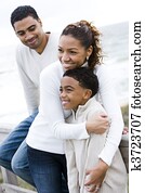 African-American family hugging at beach