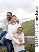 African-American family laughing and hugging at beach