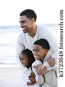 African-American father and two children on beach