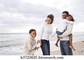 Happy African-American family of four on beach