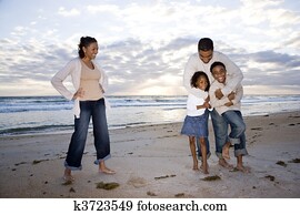Happy African-American family of four on beach