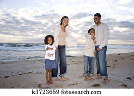 Happy African-American family of four on beach