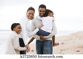 Happy African-American family of four on beach