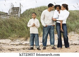Happy African-American family standing together on beach