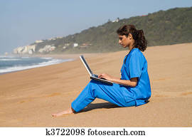 intern using laptop on beach