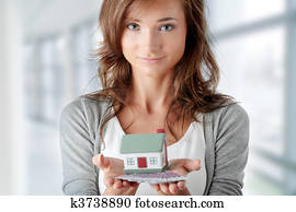 Woman holding euros bills and house model 