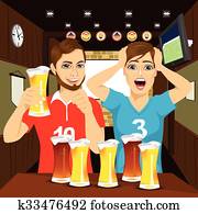 Two happy football fans cheering at bar and drinking beer